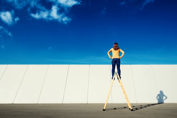 Women with a yellow sweater on a yellow ladder facing the sky